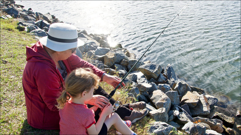 Image of adult teaching child to fish which illustrates an example of mentoring 